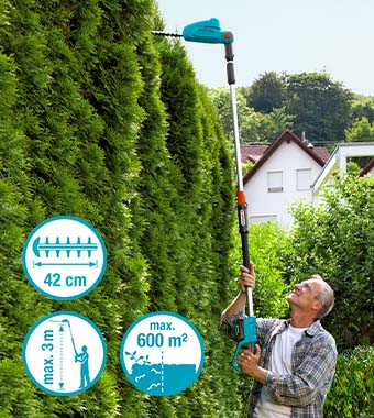 Gardener trimming tall hedge with a telescopic hedge trimmer
